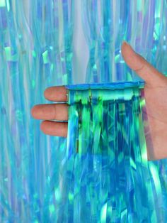 a hand holding a blue and green object in front of an abstract background with wavy lines