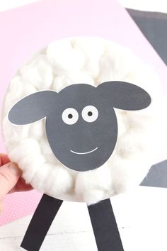 a hand holding up a paper plate with a sheep on it's face and eyes