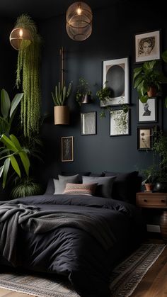 a bedroom with black walls, plants and pictures on the wall above the bedspread