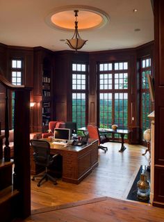 an office with wood paneling and lots of windows on the walls, along with a desk