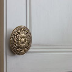 an ornate brass door handle on a white wooden door