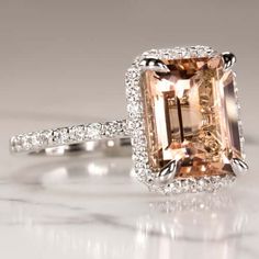 an orange and white diamond ring with diamonds around it on a marble countertop in front of a gray background