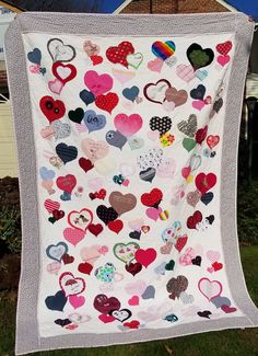 a white quilt with lots of hearts hanging from it's side on a clothesline