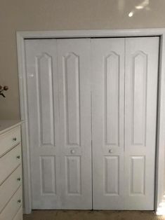 two white closet doors in a room with dressers and drawers on either side of the door