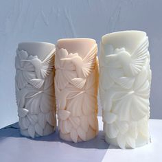 three different colored vases sitting next to each other on a white tableclothed surface