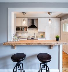 two stools are sitting at the bar in this kitchen