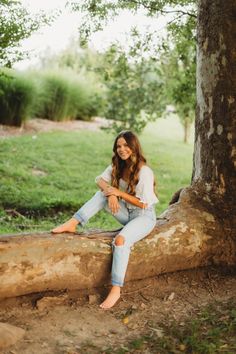 a woman sitting on a log in the woods