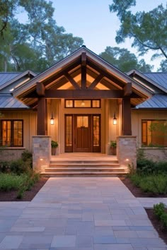 the front entrance to a house lit up at night with two lights on each side