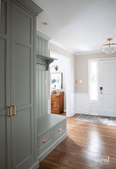 an empty room with wooden floors and gray cabinets in the corner, along with a white door