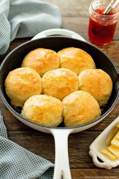 a pan filled with rolls and butter on top of a wooden table next to a bottle of ketchup