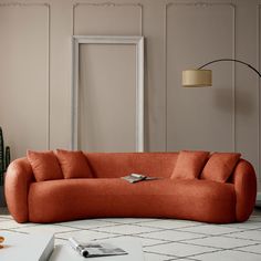 an orange couch sitting on top of a white floor next to a table and lamp