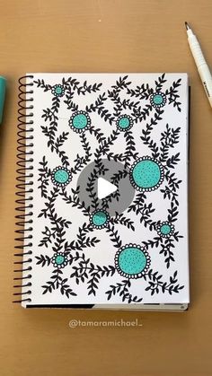 a notebook with an image of flowers on it and a pen sitting next to it