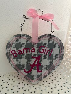 a heart shaped sign with the letter a on it and a pink bow hanging from it