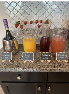 a counter topped with bottles of juice and glasses filled with liquid next to each other