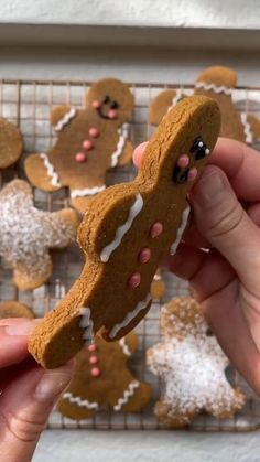 a person holding up a cookie shaped like a gingerbread man with frosting on it