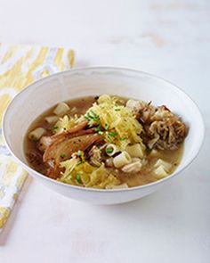 a white bowl filled with soup next to a yellow napkin on top of a table