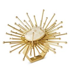 a gold plated brooch with spikes and a large white stone in the center