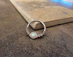 a silver ring with a white opal stone on it sitting next to a rock