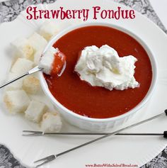 a white plate topped with a bowl of strawberry fondue and marshmallows