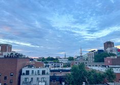 the city skyline is seen at dusk with clouds in the sky and buildings on either side