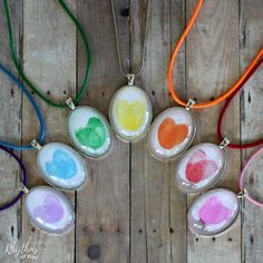 six necklaces with different colors of paint on them sitting on a wooden table next to each other