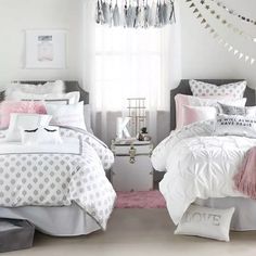 two beds with white and pink comforters in a bedroom