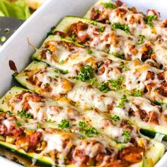 a white casserole dish filled with meat and cheese covered zucchini boats