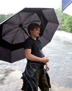 a man holding an umbrella while standing next to a river