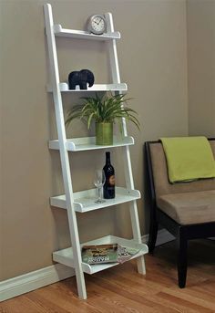 a white leaning ladder shelf next to a chair with a plant on top and a clock above it