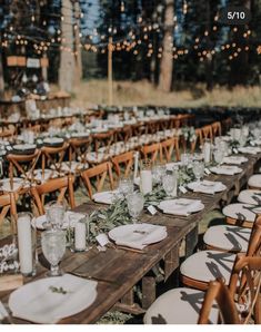 a long table set up with place settings and candles for an outdoor wedding reception in the woods