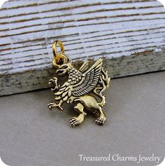 This Griffin Charm comes with a gold jump-ring as pictured. Please note that photo is not to scale and may appear larger to show detail. Refer to exact measurements below.Additional attachments (lobster clasp, large-hole bead, necklace chains) are available from the charm-attachments drop-down menu.  For a visual example of the different attachments and what each one is best suited for, scroll through the photos until you see the example photo or visit https://etsy.me/2BY7DAW for detailed inform Gold Fantasy Pendant Jewelry, Griffin Jewelry, Pandora Beads, Large Hole Beads, Necklace Charm, Bracelet Charm, Pandora Bracelet, Beaded Dangles, Jewelry Necklace