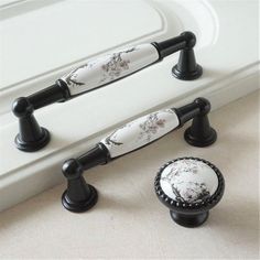 two black and white knobs on the handles of a bathtub with flowers painted on them