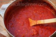 a wooden spoon in a pot of red sauce