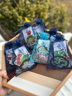 a person holding a wooden tray with small bags filled with cards and magnets on it