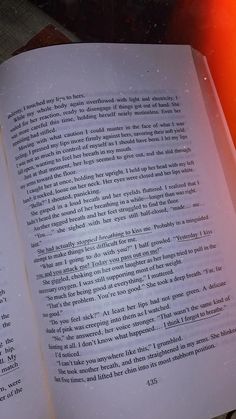 an open book sitting on top of a table next to a red lit candle and some books