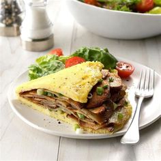 a white plate topped with an omelet and salad