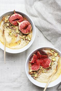 two bowls filled with fruit and oatmeal on top of a white cloth