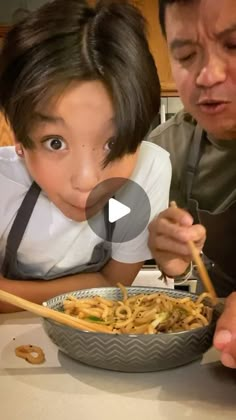 a man and child eating noodles with chopsticks