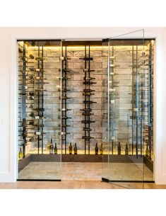 a wine cellar with glass doors and shelves full of bottles on the wall in front of it