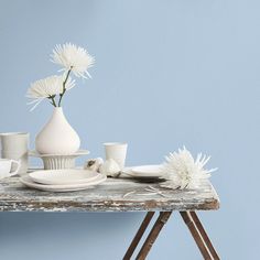 a table topped with white vases filled with flowers and plates next to each other