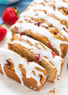 sliced strawberry bread with icing and fresh strawberries on the side, ready to be eaten