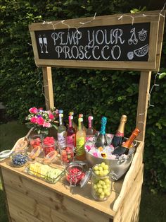 an outdoor bar with various drinks and snacks on the table, including lemons, raspberries, watermelon, and more