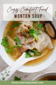 a white bowl filled with wonton soup on top of a wooden table next to a spoon