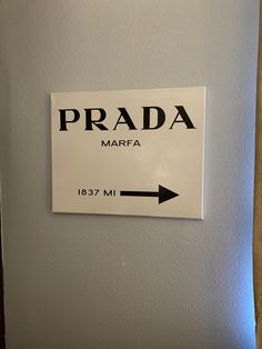 a sign that is on the side of a wall pointing to prada marfa