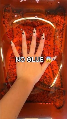 a person's hand with black and white nail polish on it, in front of an orange background