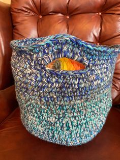 a crocheted basket sitting on top of a brown leather chair