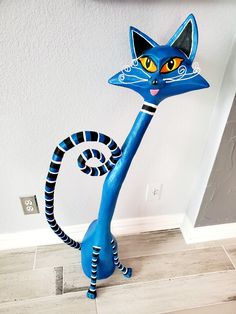 a blue and black cat statue sitting on top of a tile floor next to a wall