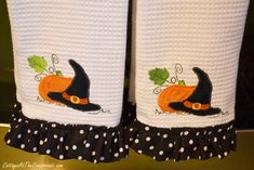 two white towels with black polka dots and a witch's hat on one towel