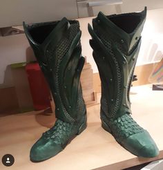 a pair of green boots sitting on top of a wooden table