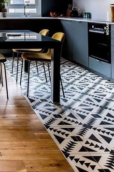 a kitchen with black and white patterned flooring next to a dining room table surrounded by yellow chairs